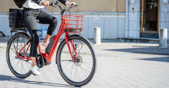 Nainen ajaa punaisella sähköpyörällä töihin