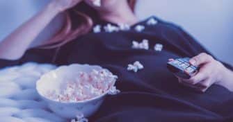 Nainen syö popcornia ja katsoo elokuvaa