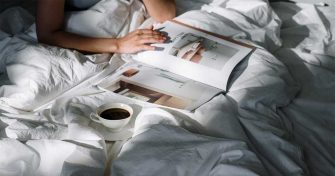 Nainen lukee lehteä sängyssä